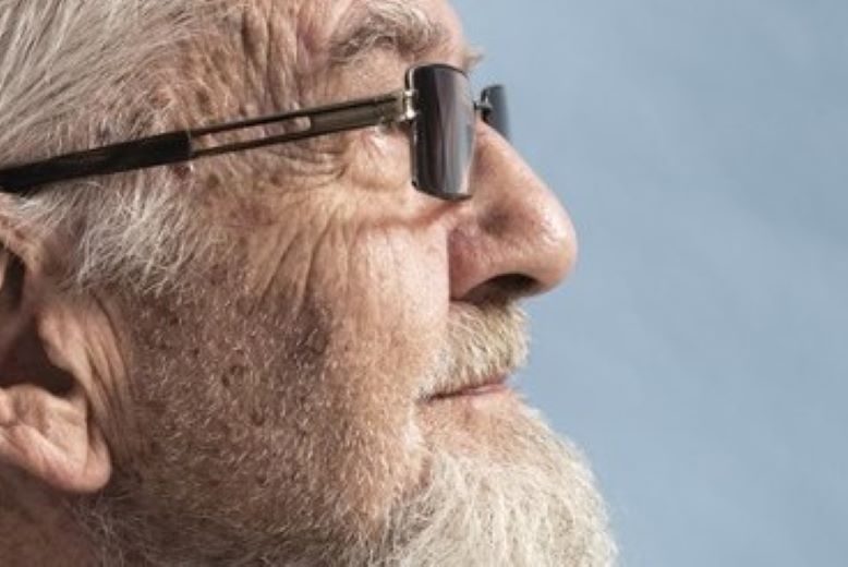 Profil starszego mężczyzny z brodą i w okularach.