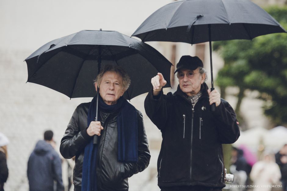 Dwóch mężczyzn pod czarnymi parasolami.