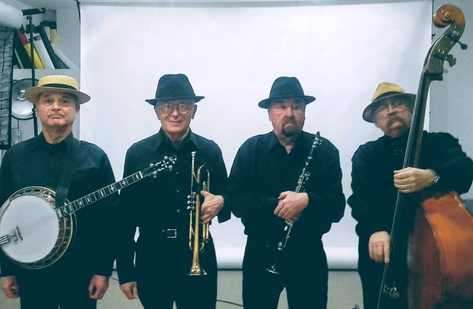 Czterech muzyków w czarnych koszulach i kapeluszach.