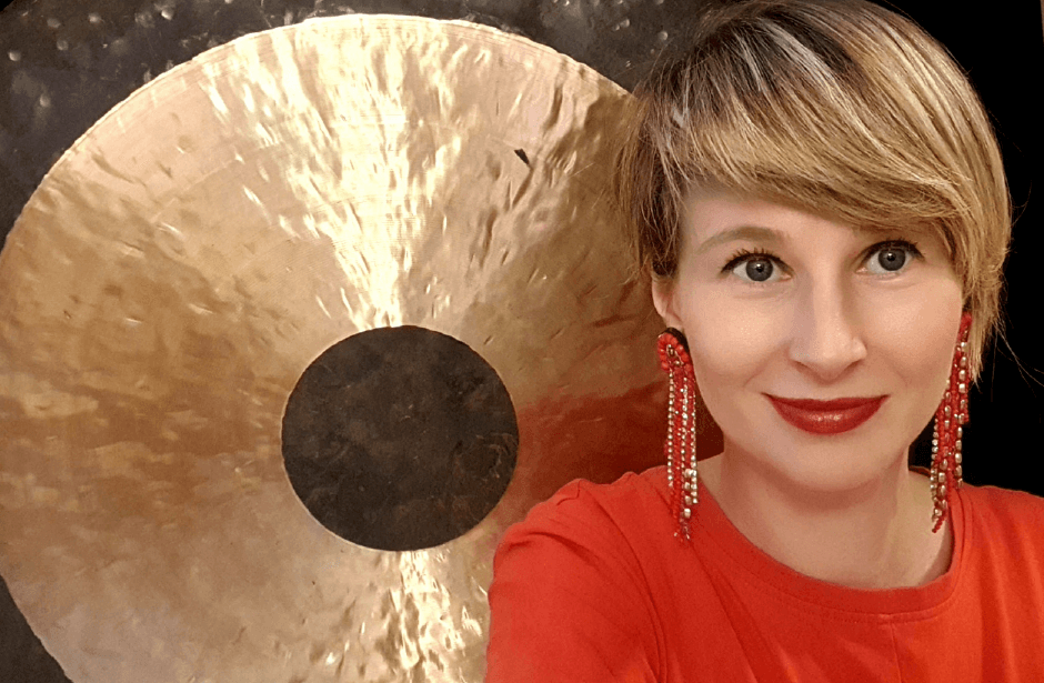 Uśmiechnięta blondynka w czerwieni na tle gongu.