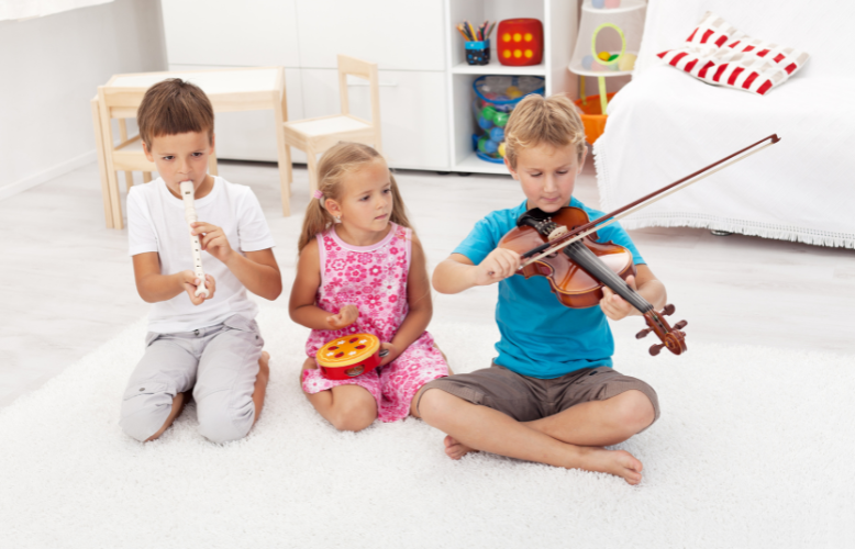 Trójka siedzi siedzi na podłodze i gra na instrumentach.