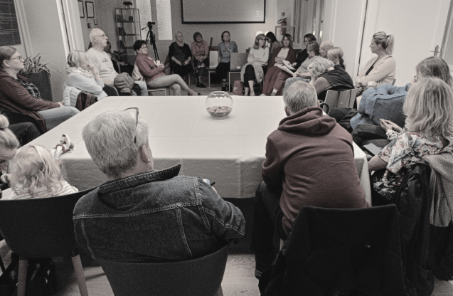 Grupa ludzi siedząca w pomieszczeniu.