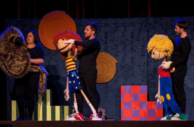 Aktorzy z dużymi lalkami na scenie.