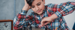 Chłopiec przestawia pionek na planszy z szachami.
