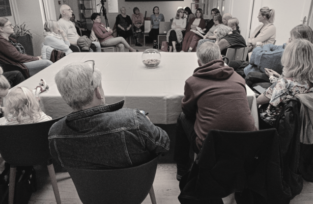 Grupa ludzi siedzących wokół stołu.