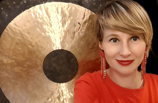 Uśmiechnięta blondynka w czerwieni na tle gongu.