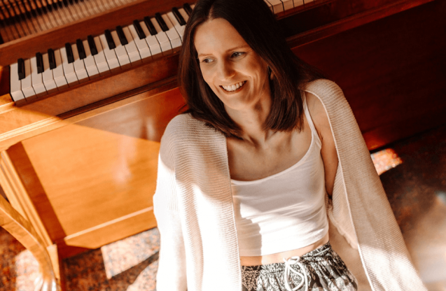 Uśmiechnięta kobieta przy pianinie.