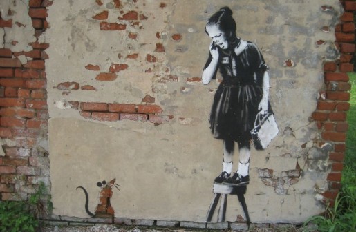 Graffiti na ścianie przedstawiające przestraszoną dziewczynkę wpatrującą się w mysz.