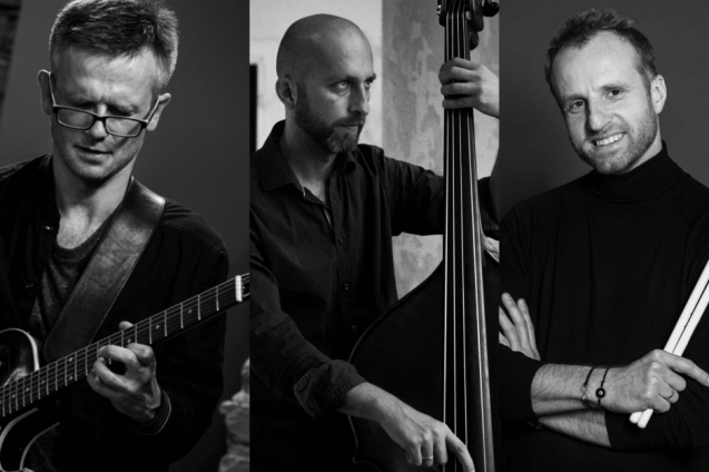 Czarno-białe zdjęcie. Trzech muzyków: gitarzysta, perkusista i kontrabasista.